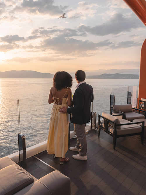 Woman in yellow shirt wheeling suitcase aboard Celebrity cruise ship resort deck