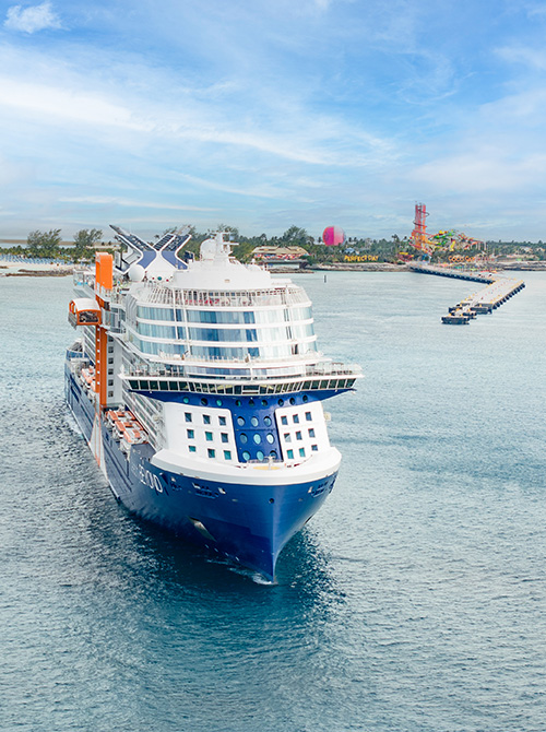 Woman in yellow shirt wheeling suitcase aboard Celebrity cruise ship resort deck
